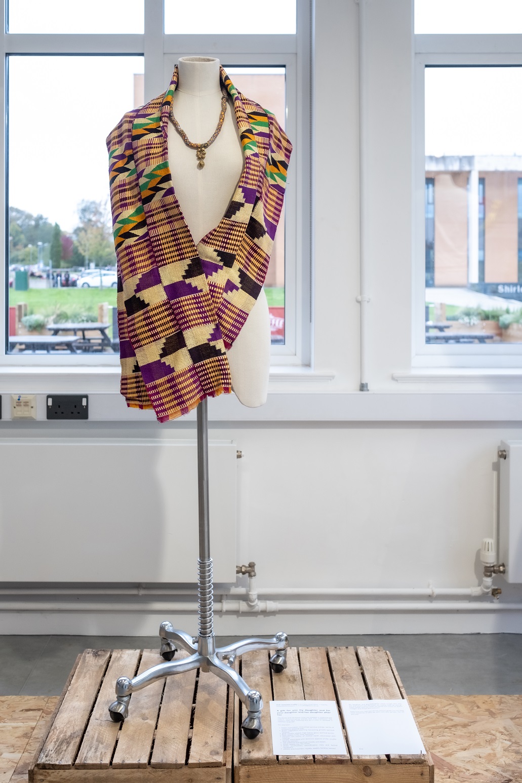 A graphically stitched shawl in purple, black, cream, green and orange colours